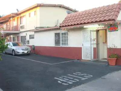 a car parked in a parking lot in front of a building at American Inn in South El Monte