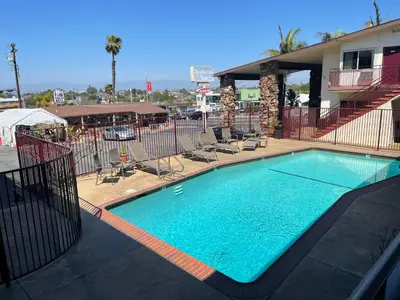 a large swimming pool with chairs and a building at Seahorse Inn Manhattan Beach - LAX in Manhattan Beach