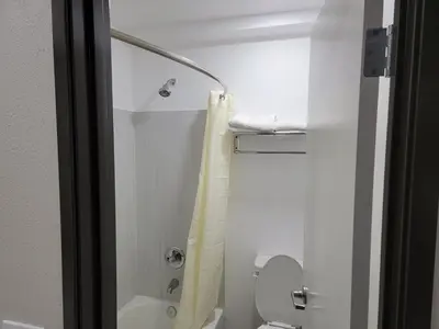 a small bathroom with a shower and a toilet at Travelodge by Wyndham Buena Park in Buena Park