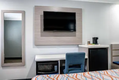 a room with a desk and a tv on a wall at Travelodge Inn & Suites by Wyndham Bell Los Angeles Area in Bell