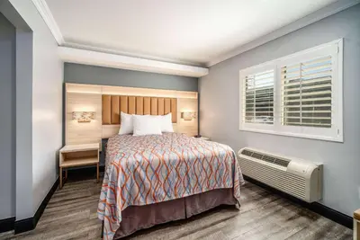 a bedroom with a bed and a desk and a window at Travelodge Inn & Suites by Wyndham Bell Los Angeles Area in Bell