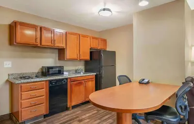 a kitchen with a wooden table and a table and a refrigerator at Extended Stay America Suites - Bakersfield - Chester Lane in Bakersfield