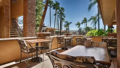 an outdoor patio with tables and chairs and palm trees at Empire Inn in San Bernardino