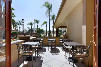a patio with tables and chairs and palm trees at Empire Inn in San Bernardino