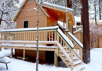a cabin with a deck in the snow at Sleepy Forest Cottages in Big Bear Lake