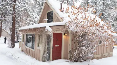 a house with a red door in the snow at Sleepy Forest Cottages in Big Bear Lake