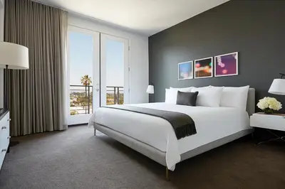 a bedroom with a large white bed and a large window at AKA Beverly Hills in Los Angeles