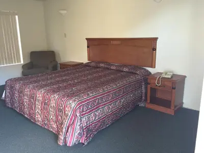 a bedroom with a bed and a telephone and a chair at Golden Hills Motel in Tehachapi