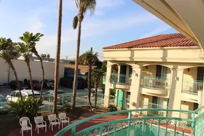 a view of a building with palm trees and a swimming pool at LYFE INN & SUITES by AGA - LAX Airport in Inglewood