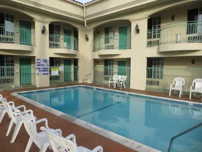 a pool in the courtyard of a hotel with white chairs at LYFE INN & SUITES by AGA - LAX Airport in Inglewood