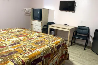 a bedroom with a bed and a desk and a television at Travel Inn Downtown LA in Los Angeles
