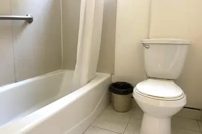 a bathroom with a white toilet and a bath tub at Travel Inn Downtown LA in Los Angeles