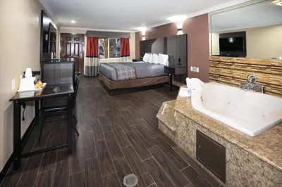a hotel room with a tub and a bed at Rodeway Inn & Suites Bellflower in Bellflower