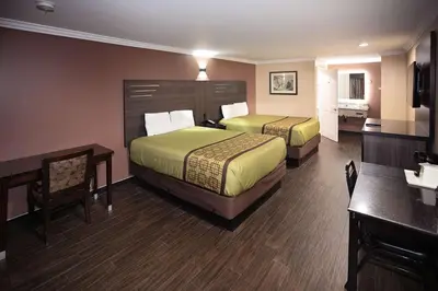 a hotel room with two beds and a desk at Rodeway Inn & Suites Bellflower in Bellflower