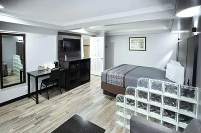 a hotel room with a bed and a desk and a television at Rodeway Inn & Suites Bellflower in Bellflower