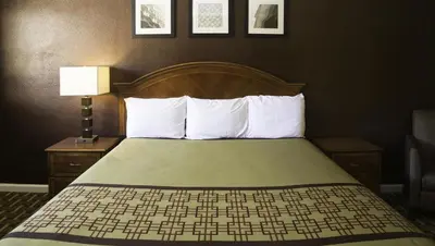a hotel room with a bed with white pillows at Kings Motel Inglewood in Inglewood