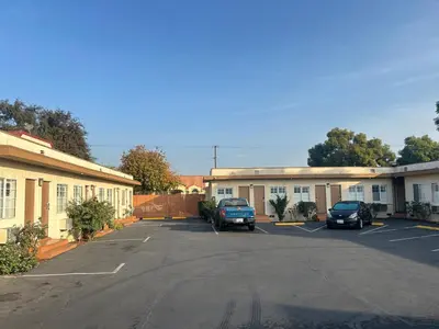 a parking lot with cars parked in front of buildings at Budget Inn Motel in South Gate