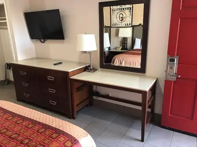 a bedroom with a dresser and a mirror and a bed at Economy Inn LAX Inglewood in Inglewood