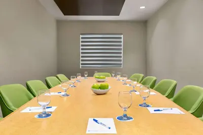 a conference room with a long table and green chairs at Wyndham Anaheim in Anaheim