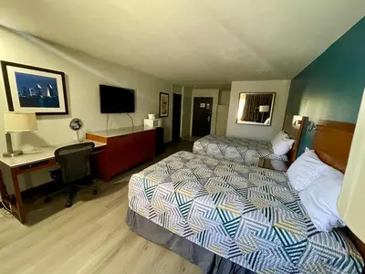 a hotel room with two beds and a desk at Portside Inn & suites in San Pedro