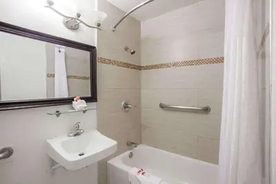 a bathroom with a sink and a toilet and a tub at Days Inn by Wyndham Orange Anaheim in Orange