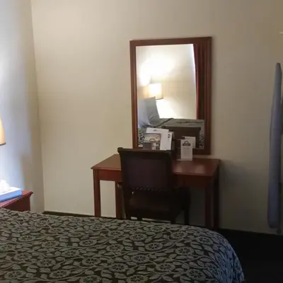 a hotel room with a desk and a mirror at Days Inn by Wyndham Orange Anaheim in Orange