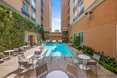 an outdoor patio with tables and chairs and a swimming pool at Hyatt Place Riverside Downtown in Riverside