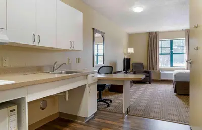 a kitchen with a desk and a room with a bed at Extended Stay America Suites - Los Angeles - Ontario Airport in Guasti