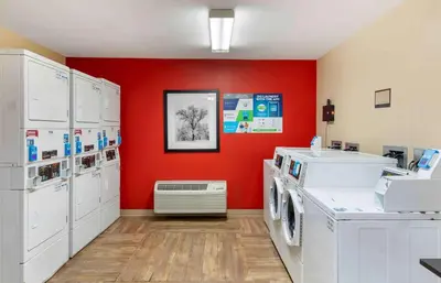 a laundry room with white washers and a red wall at Extended Stay America Suites - Los Angeles - Ontario Airport in Guasti
