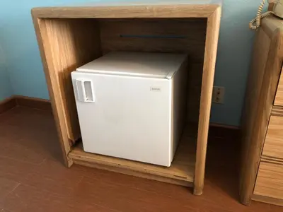 a small white refrigerator in a wooden cabinet at Chester Inn Motel in Stanton
