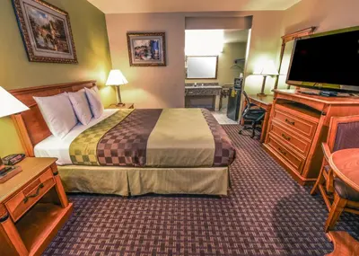 a hotel room with a bed and a flat screen tv at Chariot Inn Glendale - Pasadena in Glendale