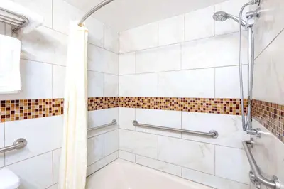 a white bathroom with a shower and a tub at Travelodge by Wyndham Harbor City in Harbor City