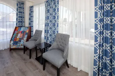 two chairs and a table in a room with blue and white curtains at Travelodge by Wyndham Harbor City in Harbor City