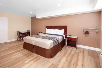a hotel room with a bed and a table at Travelodge by Wyndham Harbor City in Harbor City