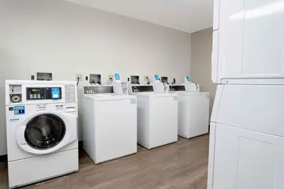 a laundry room with four washing machines and a refrigerator at Extended Stay America Suites - Los Angeles - Torrance - Del Amo Circle in Torrance