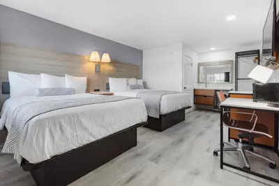 a hotel room with two beds and a desk at Inland Inn & Suites in San Bernardino