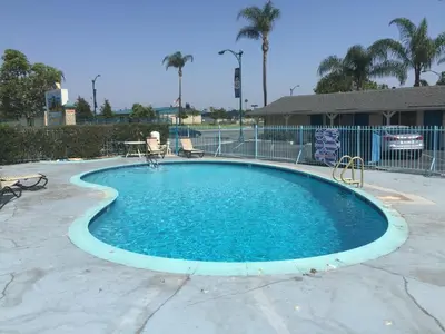 a large swimming pool with blue water in a yard at Frontier Motel in Anaheim
