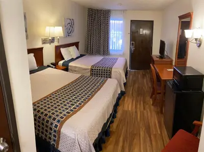 a hotel room with two beds and a desk at Vantage Point Inn - Woodland Hills in Woodland Hills