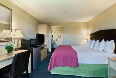 a hotel room with a large bed and a desk at Oxnard Inn Lancaster in Lancaster