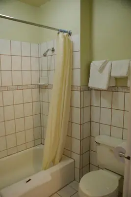 a bathroom with a toilet and a tub and a sink at Sahara Motel in Anaheim