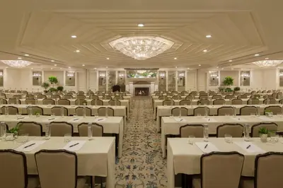 a banquet hall with white tables and chairs and a chandelier at Shutters On The Beach in Los Angeles