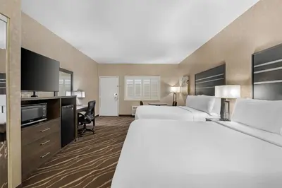 a hotel room with two beds and a flat screen tv at Best Western Plus Park Place Inn - Mini Suites in Anaheim