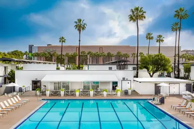 a swimming pool with chairs and a building at Anaheim Hotel in Anaheim