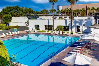 a large swimming pool with chairs and umbrellas at Anaheim Hotel in Anaheim