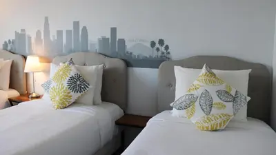 two beds sitting next to each other in a bedroom at Hometel Suites in Los Angeles