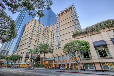 a building with palm trees in front of tall buildings at Omni Los Angeles Hotel in Los Angeles
