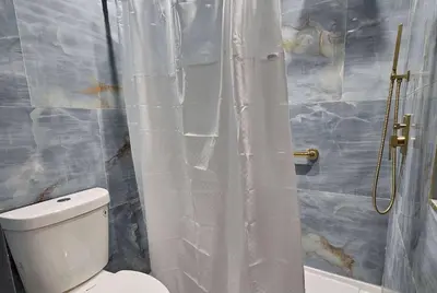 a bathroom with a toilet and a shower curtain at Travelodge Inn & Suites by Wyndham Fullerton in Fullerton