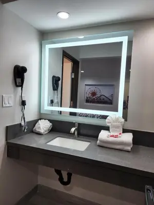 a bathroom with a sink and a large mirror at Travelodge Inn & Suites by Wyndham Fullerton in Fullerton