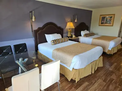 a hotel room with two beds and a table at Fullerton Inn in Fullerton