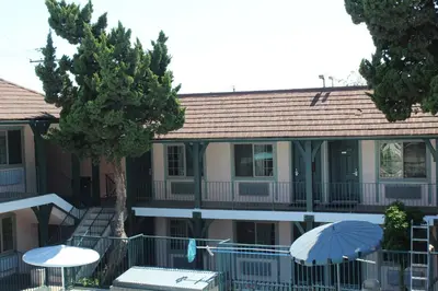 a building with tables and umbrellas in front of it at Best Whittier Inn in Whittier